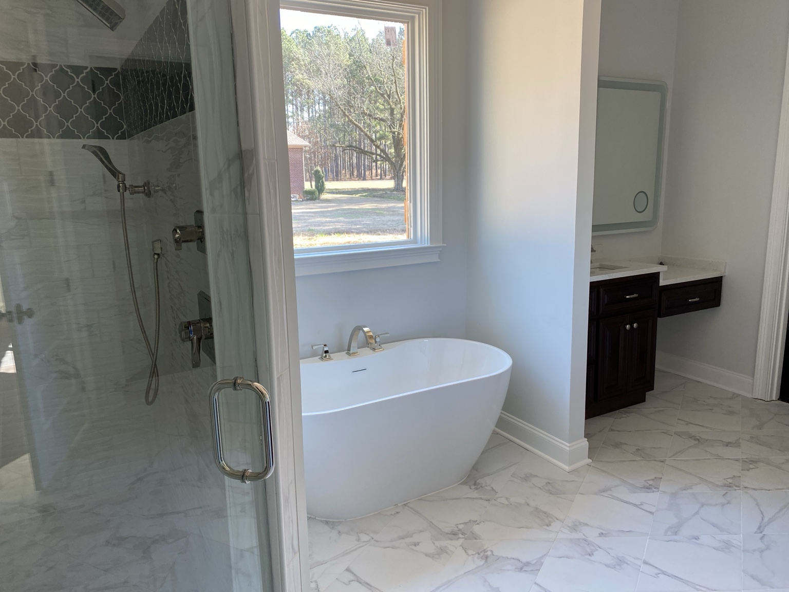 Completed bathroom plumbing project with glass shower, freestanding tub and installed fixtures